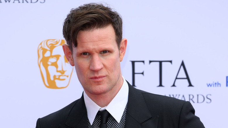 Matt Smith wearing a black suit and polka-dot shirt and black tie at a red carpet event