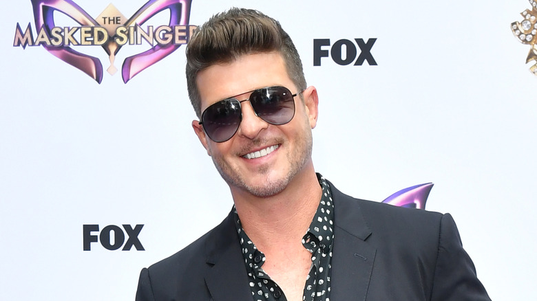 Robin Thicke in suit and sunglasses smiling on red carpet