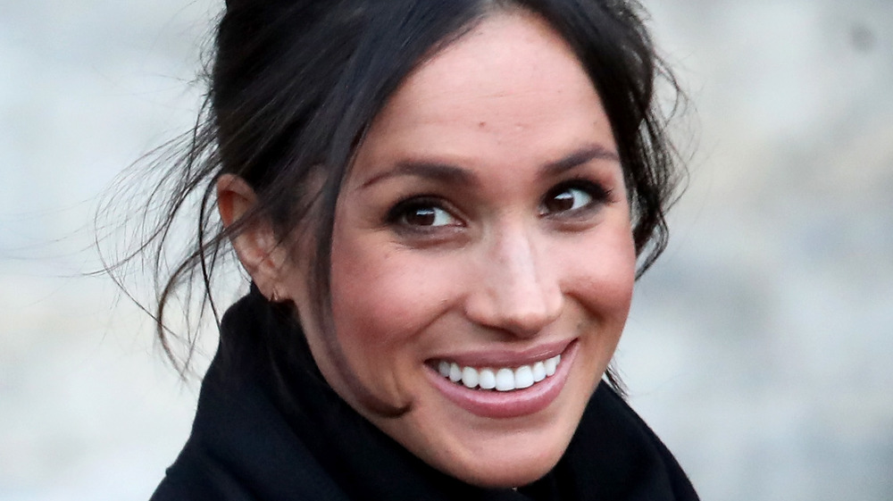 Meghan Markle smiling with her hair in an updo