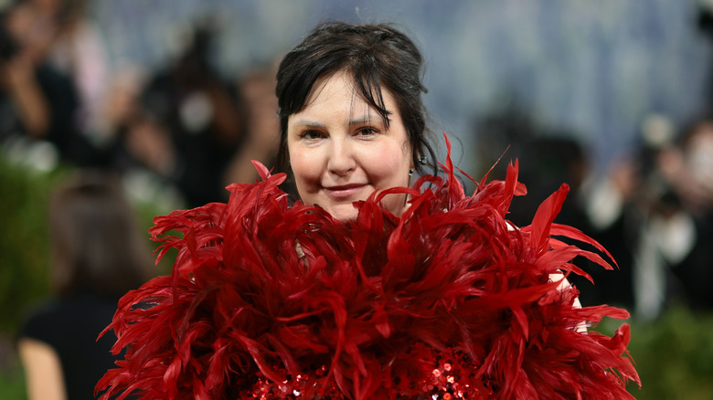 Lena Duna close-up at the Met Gala wearing a red feathered dress.