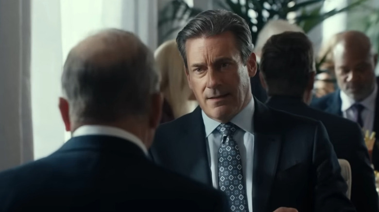 Jon Hamm wearing a suit appears in Landman seated across from another man at a restaurant