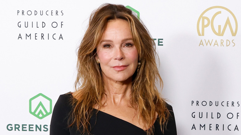 Jennifer Grey posing in black dress with asymmetrical neckline