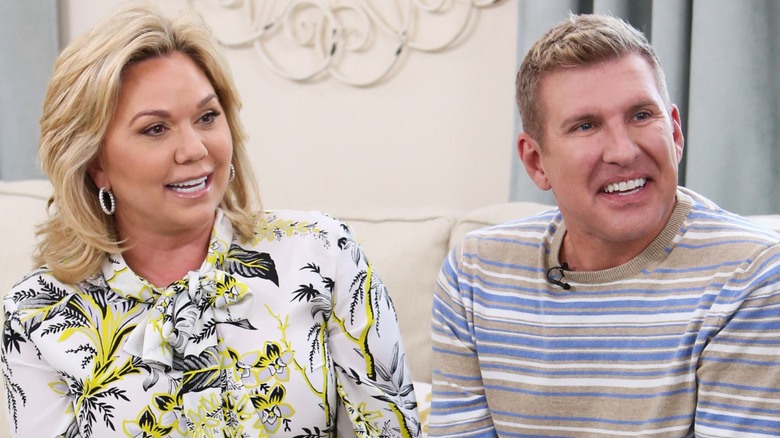 Todd and Julie Chrisley happily glance sideways while seated.