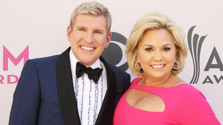 Todd and Julie Chrisley lean on each other as they display broad smiles.