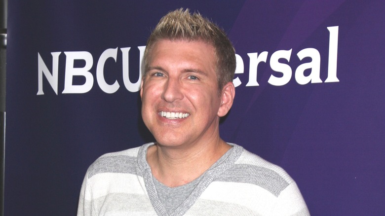 Sporting a stripped gray and white sweater, Todd Chrisley is all smiles.