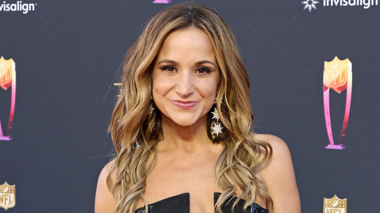 Dianna Russini smiling while posing on the red carpet in a black strapless dress