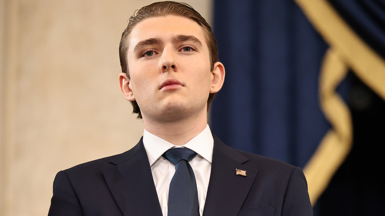 Barron Trump in a suit looking straight ahead with a serious expression