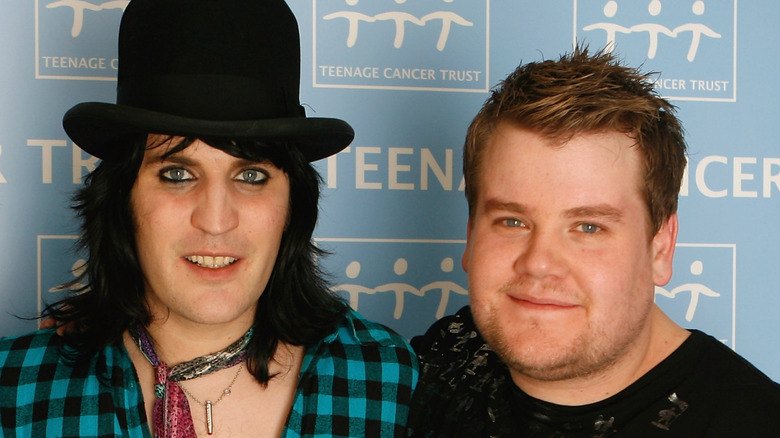 Comedian Noel Fielding in a top hat with James Corden on the red carpet