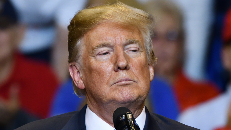 Donald Trump looking serious in front of microphone