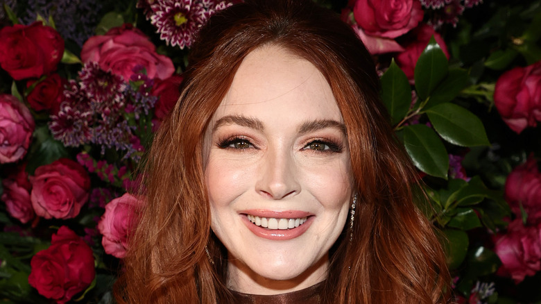 Lindsay Lohan smiling in front of flower wall 