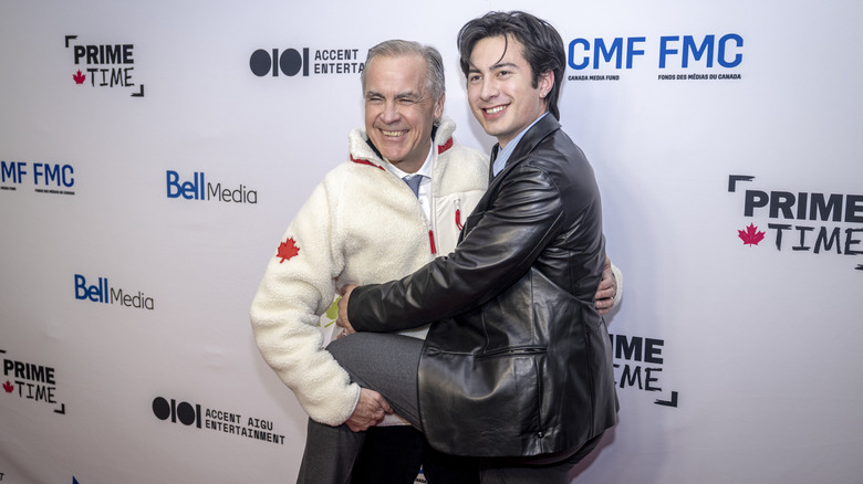 Hudson Williams smiling with his leg around Canadian Prime Minister Mark Carney