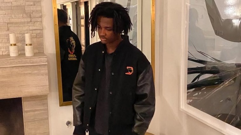 Ryan Breaux wearing a black bomber jacket and standing in front of a mirror