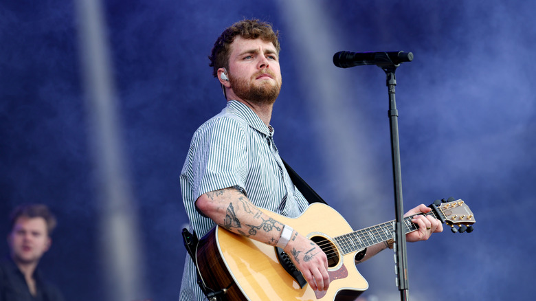 Alex Warren playing guitar during concert
