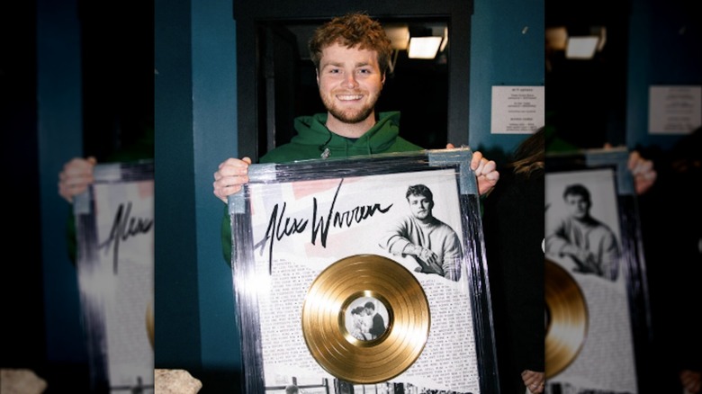 Alex Warren displaying his gold record