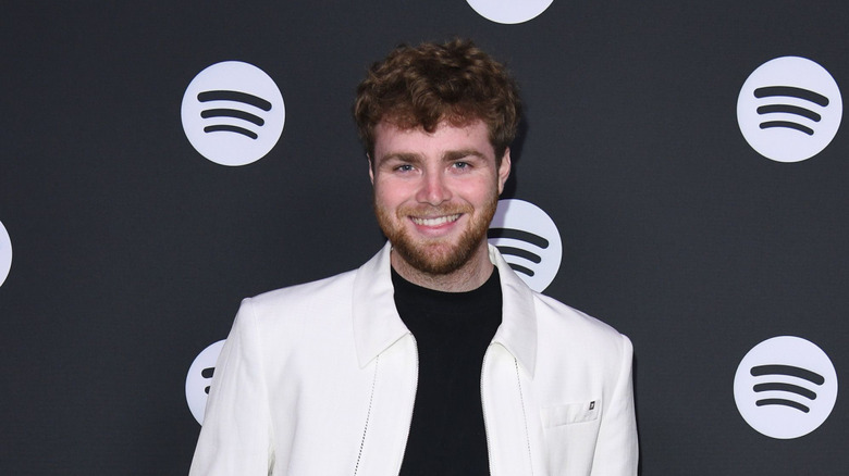 Alex Warren posing in front of black Spotify background