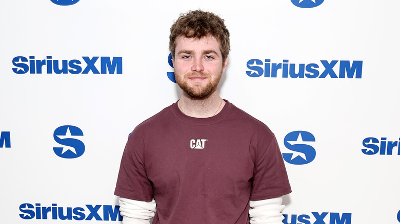 Alex Warren posing in front of SiriusXM background