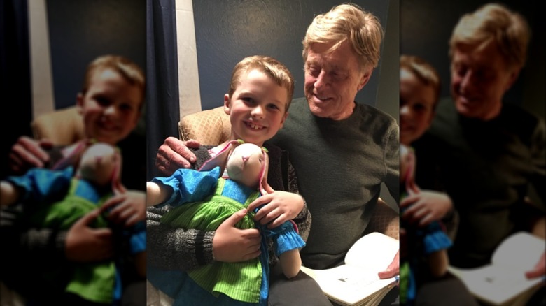 Iain Armitage pictured holding a stuffed bunny toy while seated beside Robert Redford.