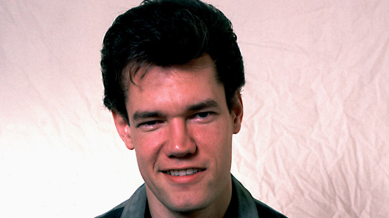 Young Randy Travis posing for a portrait photo against a pale pink backdrop
