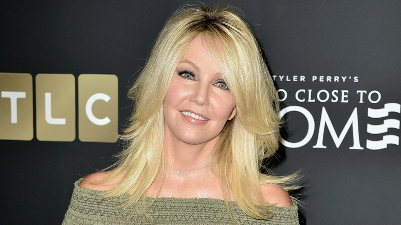 Heather Locklear at a red carpet event wearing a green cold shoulder sweater top