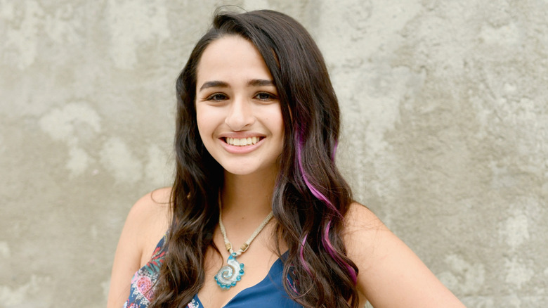 Jazz Jennings, sporting wavy hair and a colourful outfit, flashing a bright smile.