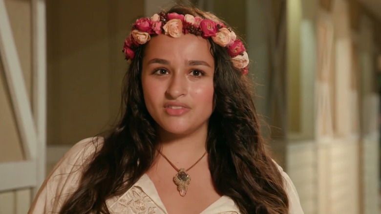 Jazz Jennings gazing into the camera while wearing a floral headpiece and a seashell necklace.