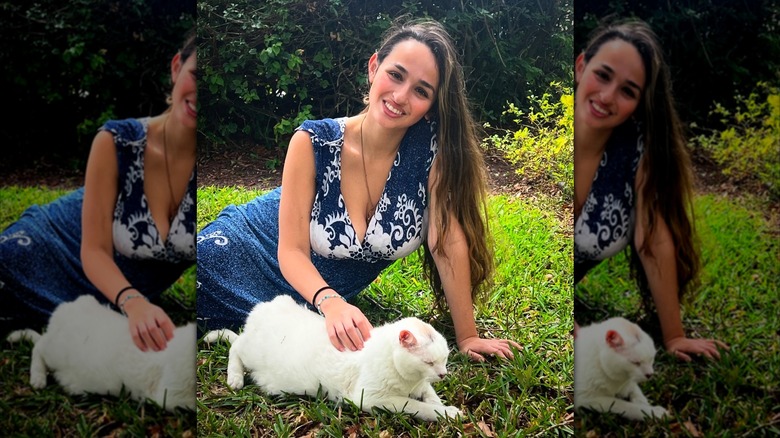 Jazz Jennings brushing her pet Nemo's fur while seated on the grass.