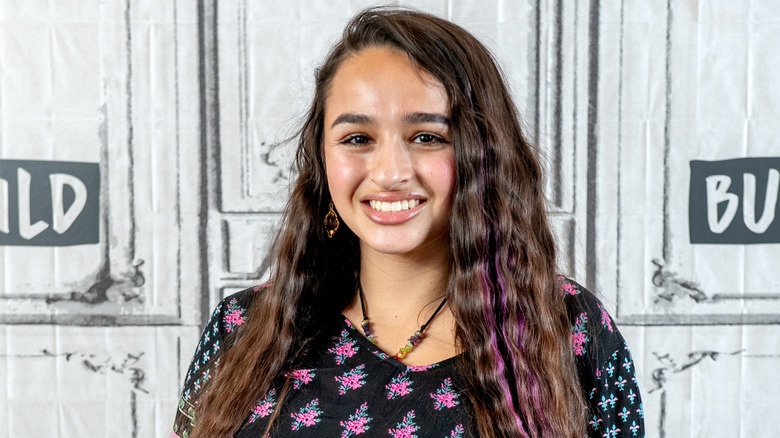 Jazz Jennings smiling and wearing wavy hair with purple tips.