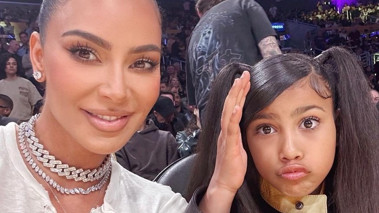 Kim Kardashian smiling, North West holding hand up 