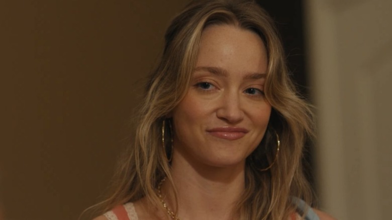 Francesca Xuereb smiling and wearing large hoop earrings while in character on 