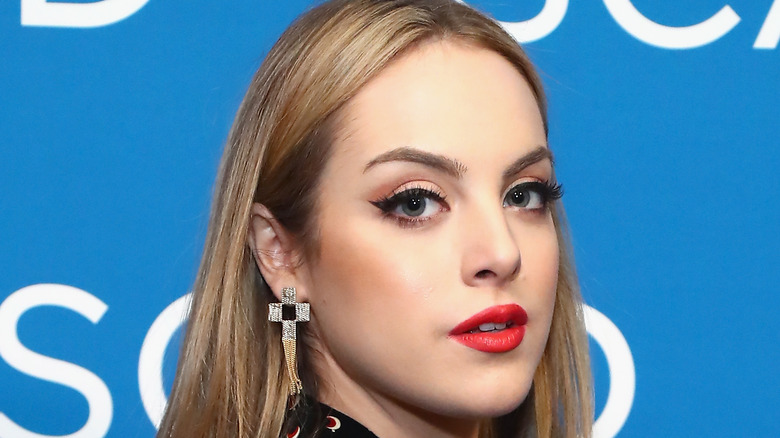 Liz Gillies with blonde hair in an off the shoulder pose