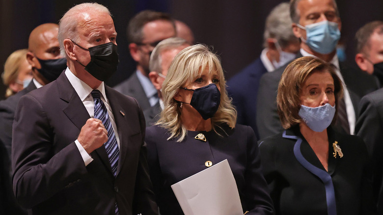 Joe Biden, Jill Biden and Nancy Pelosi stand together at a funeral.