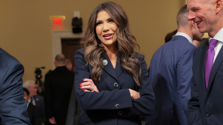 Kristi Noem laughing with her arms folded.