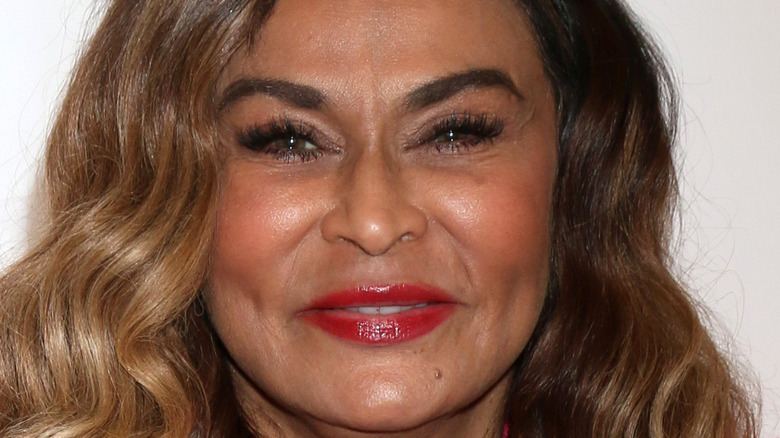Tina Knowles smiles in a pink blazer and teal blouse