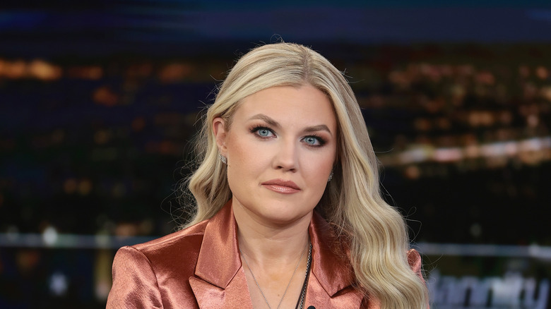 Erika Kirk photographed with a straight face in a shiny peach blouse