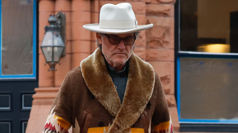 Kurt Russell walks the streets in Western attire