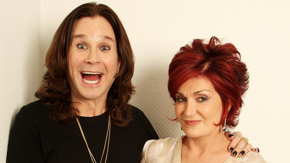 Ozzy Osbourne smiling big and Sharon Osbourne smirking