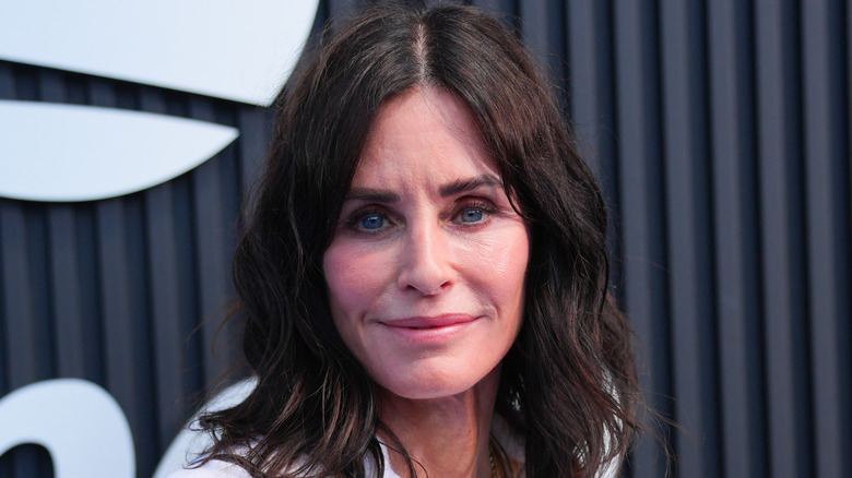 Friends star Corteney Cox smiles on the red carpet wearing sunglasses