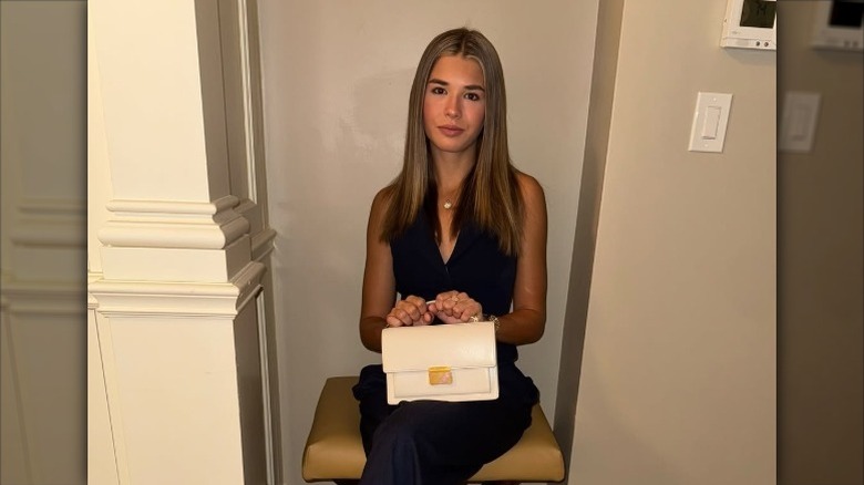 Kai Trump sits holding a Golden Goose handbag in her lap