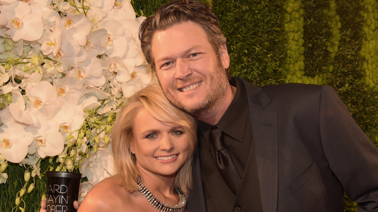 Miranda Lambert and Blake Shelton posing in front of flowers