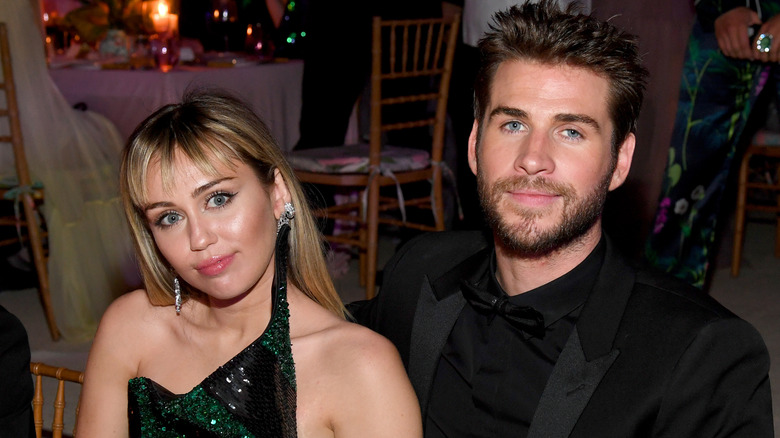 Miley Cyrus and Liam Hemsworth seated at a table