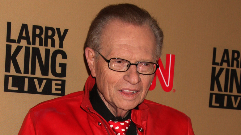 Larry King posing in red jacket