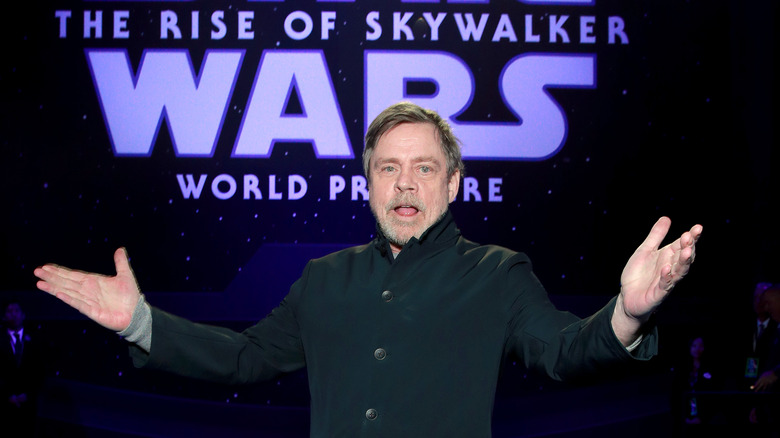 Mark Hamill holding his hands upward at an event