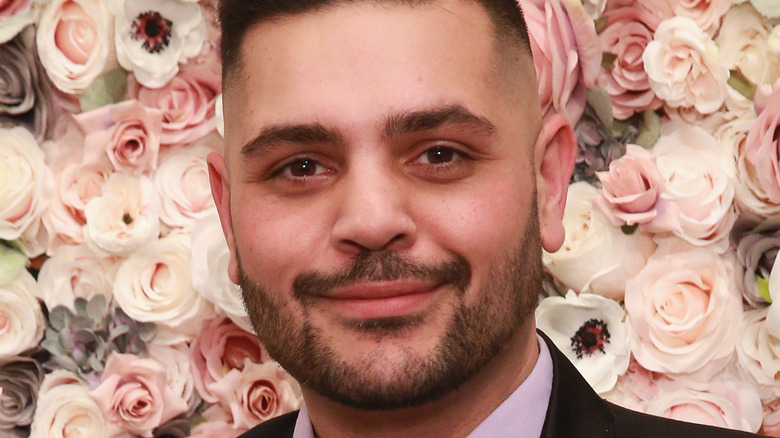 Michael Costello in front of a wall of flowers