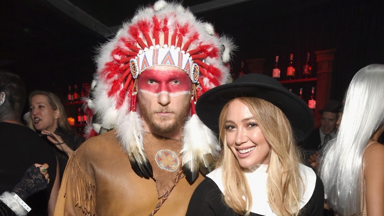 Wearing a Pilgrim Indian costume, Hilary Duff smiles next to a serious Jason Walsh, who is in a Native American costume