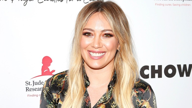 Wearing a collared black patterned look, Hilary Duff is all smiles