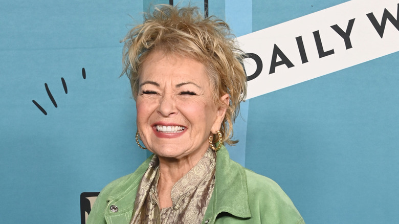 Roseanne Barr smiles in a green jacket at a Daily Wire event