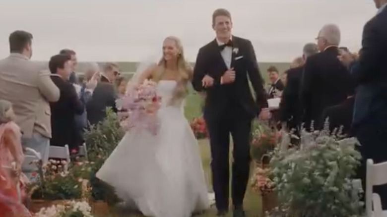 Paige Drummond and David Andersen walk down the aisle as wedding guests clap.