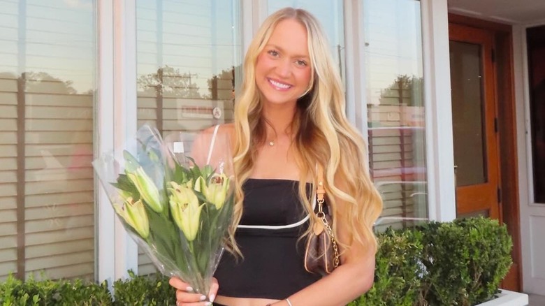Paige Drummond smiles with her head tilted to the side as she holds a bouquet of flowers.