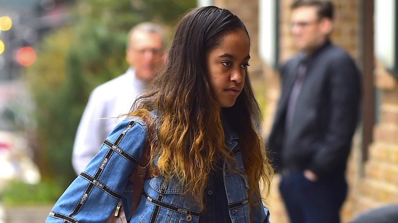 Dressed in a denim number, Malia Obama walks with her eyes looking at the ground.