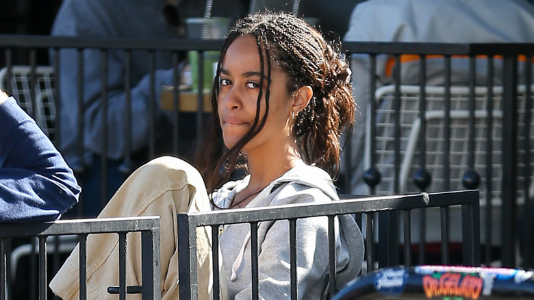 Malia Obama sitting at a restaurant with pursed lips